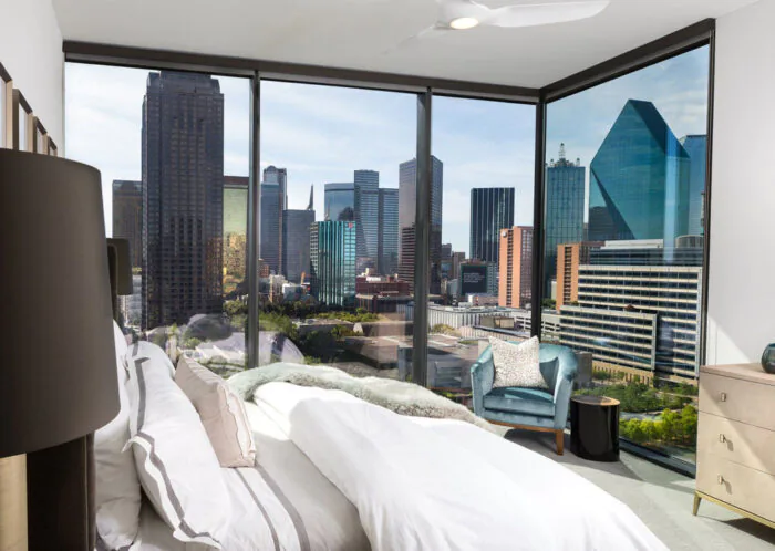 A bedroom with a city view and large glass panels