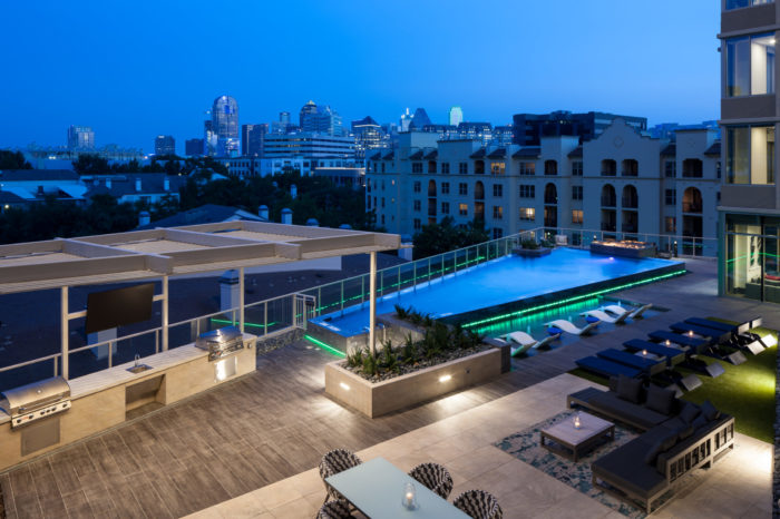 A view of a rooftop pool with neon green lights on it