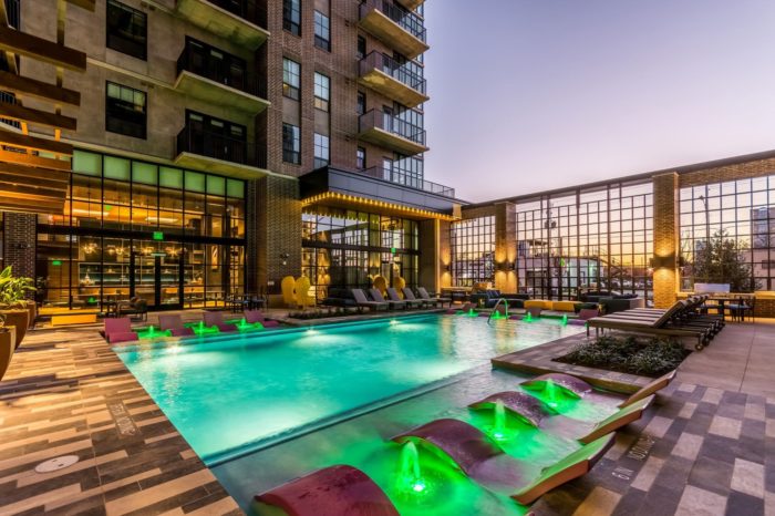 Pool in a condo with lounge chairs and green lights on the water