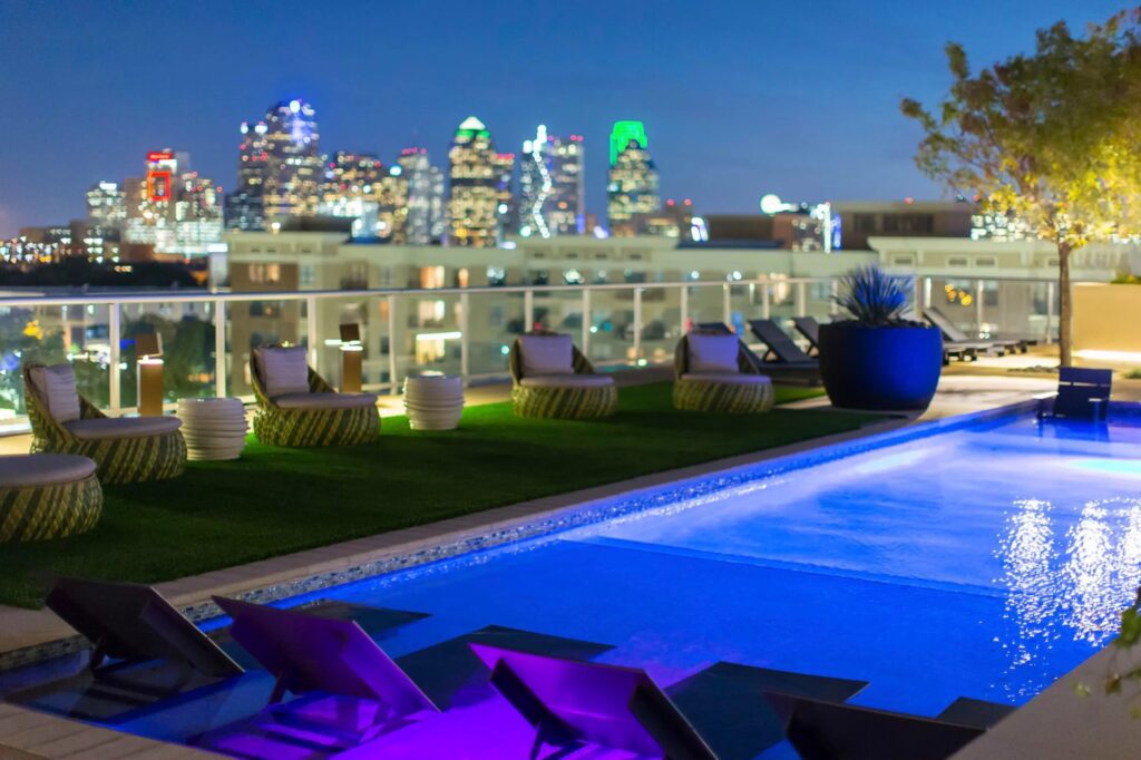 A rooftop pool with lounge chairs and a view of the city from 3700m high-rise apartments in Dallas.