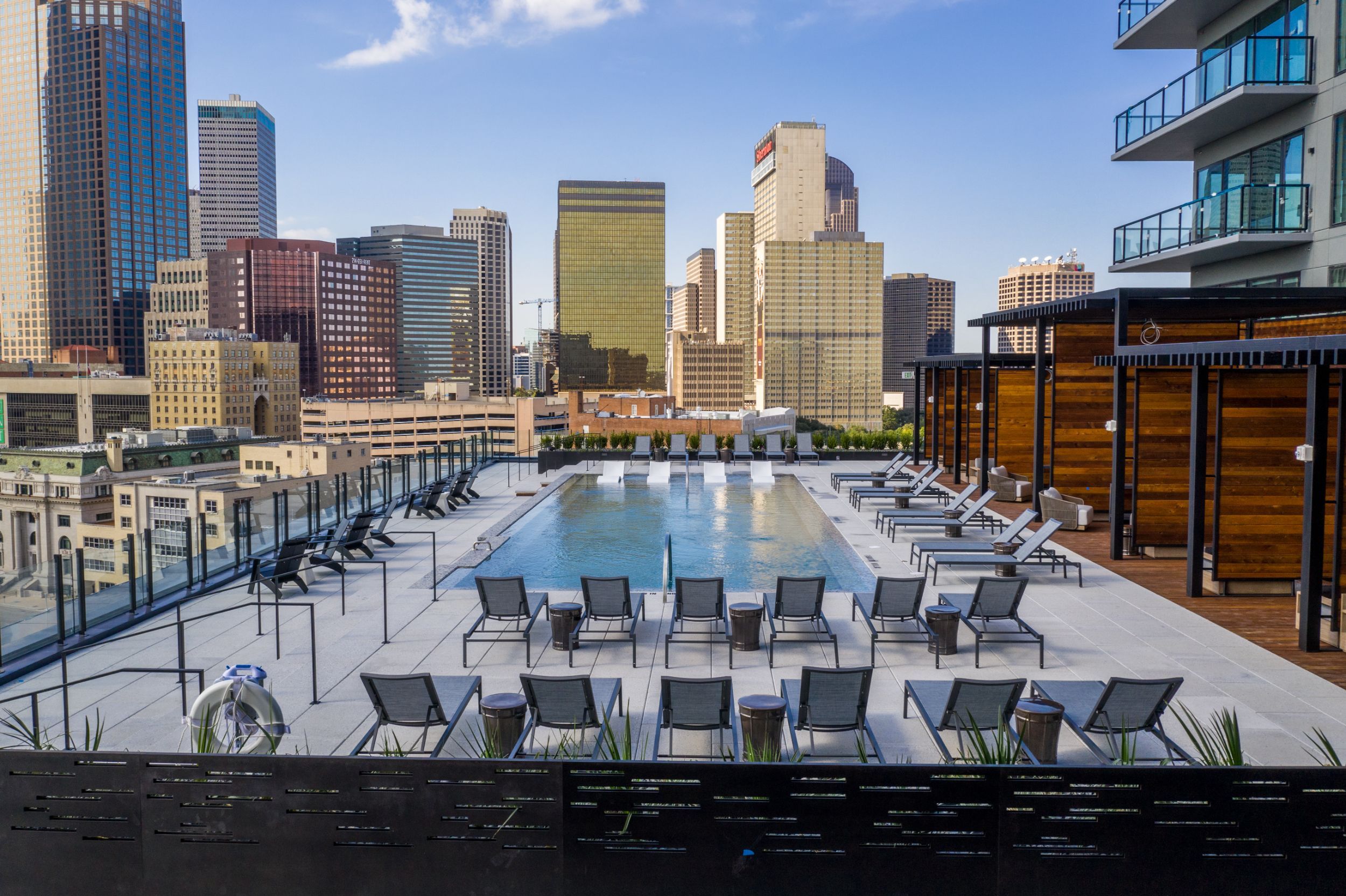 New East Quarter downtown Dallas apartments with a rooftop pool offering lounge chairs and a stunning view of the city.
