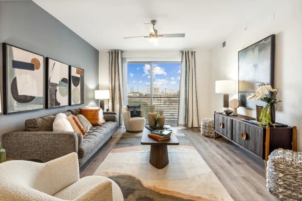 Modern apartment living room at The Margaret at Riverfront in Dallas Texas with natural light and balcony view near Uptown Dallas.