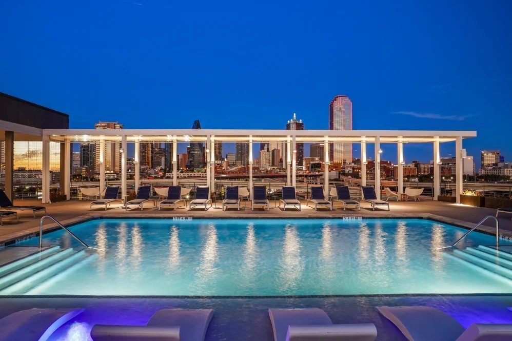 Rooftop pool at The Margaret at Riverfront in Dallas Texas at night with downtown skyline views near Uptown Dallas.